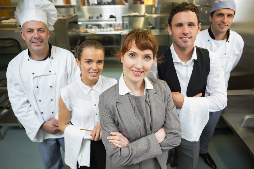 Cute female manager posing with the staff in a modern kitchen